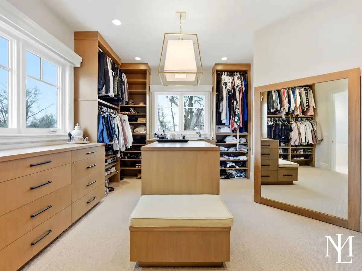 Spacious custom walk-in closet with center island, built-in storage, and full-length mirror in luxury Huntsville residence.