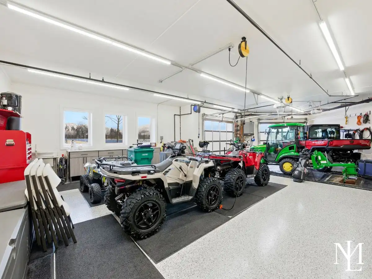 Oversized garage with epoxy floors, utility vehicles, storage cabinetry, and space for recreational equipment in custom Huntsville estate.