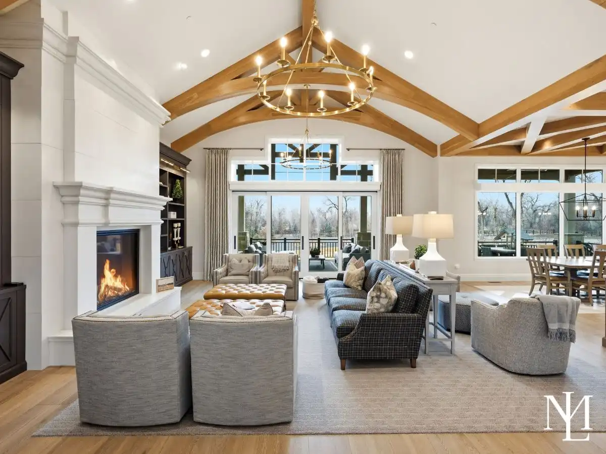 Vaulted great room with exposed timber trusses, statement chandelier, fireplace, and open layout in luxury Ogden Valley residence.