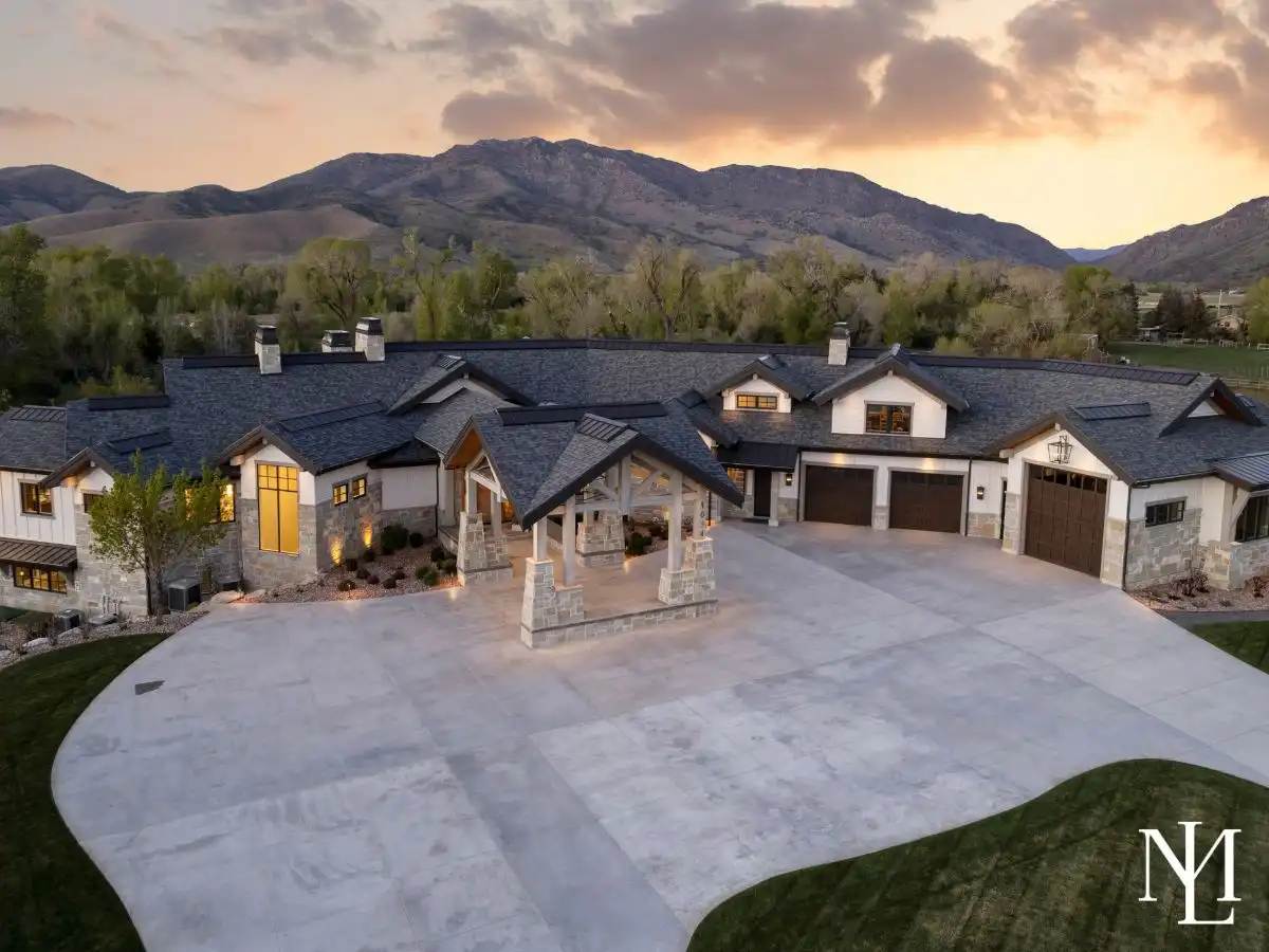 Twilight aerial view of luxury Huntsville Utah estate with expansive driveway, porte cochere, and mountain backdrop in Ogden Valley.