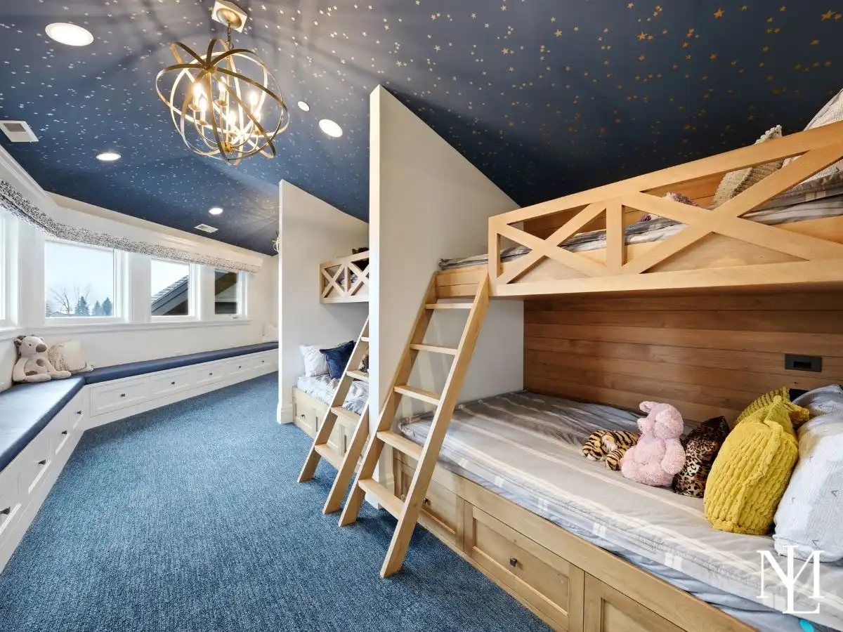 Custom bunk room with built-in beds, starry ceiling, window bench seating, and playful luxury design for guests or kids.