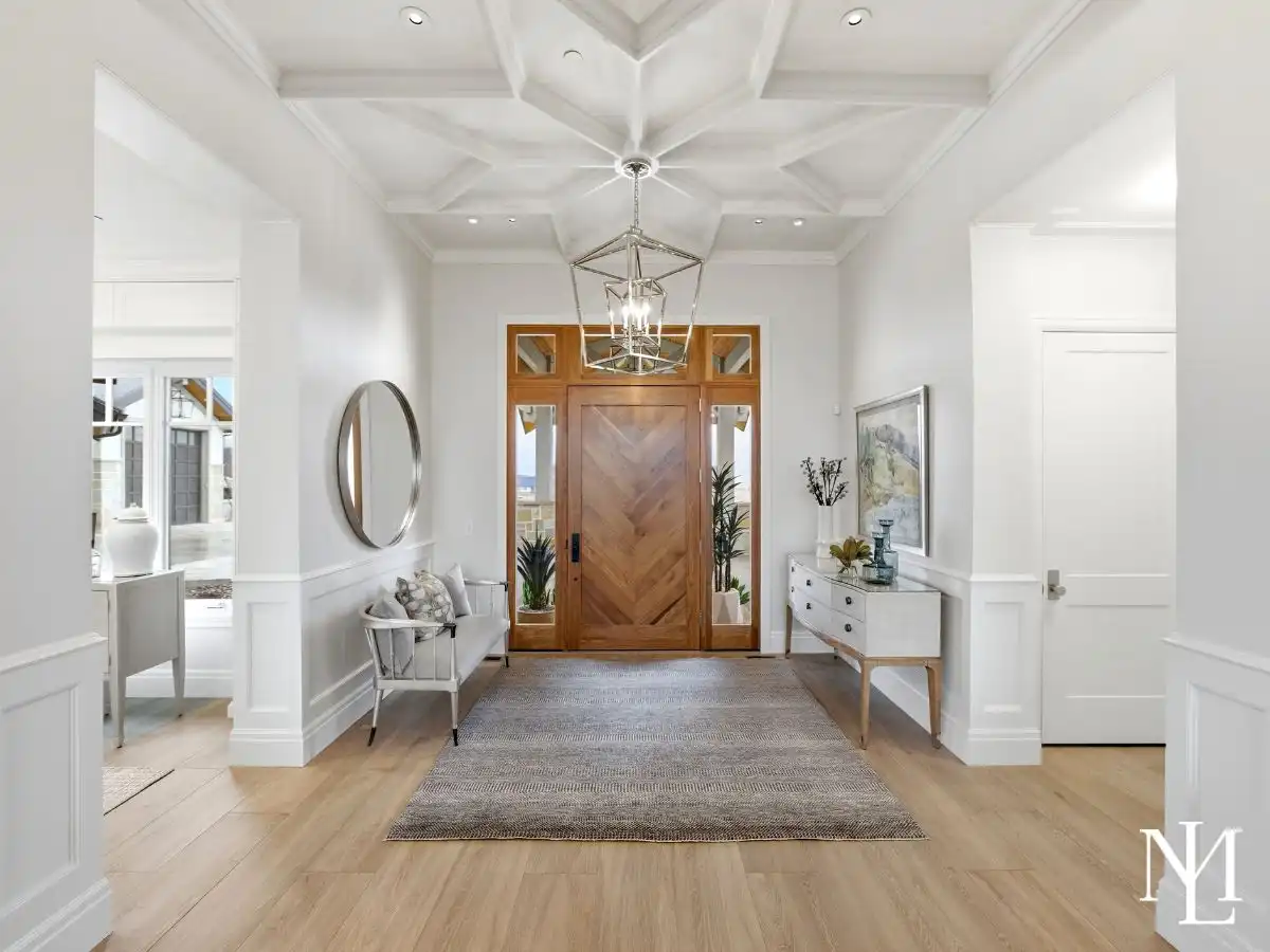 Bright entry foyer with chevron wood front door, coffered ceiling, and refined white millwork in luxury Huntsville home.