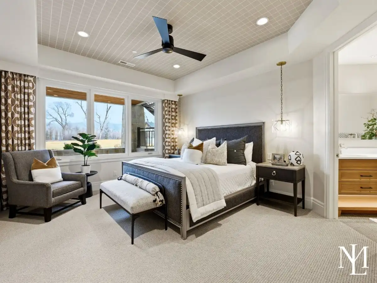 Stylish guest bedroom with large window, designer lighting, and adjoining bath in luxury Huntsville Utah home.