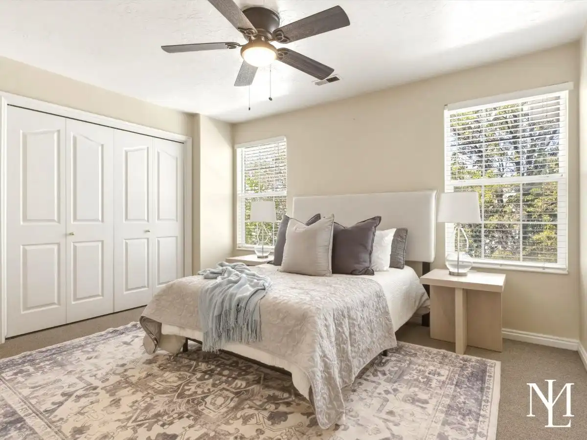 Primary bedroom in Draper townhome with large windows, ceiling fan, neutral carpet, and bright natural light