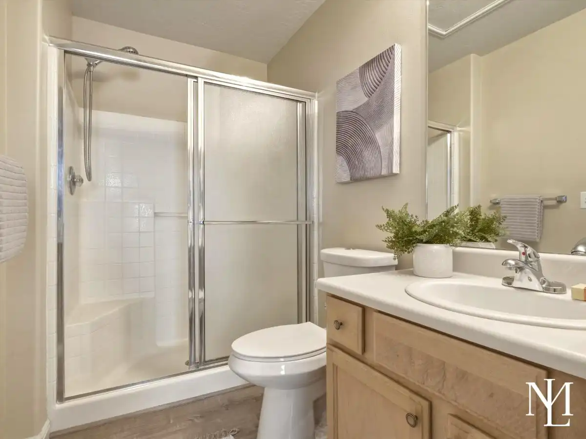 Full bathroom in Draper townhome with glass shower door, wood vanity, large mirror, and neutral finishes