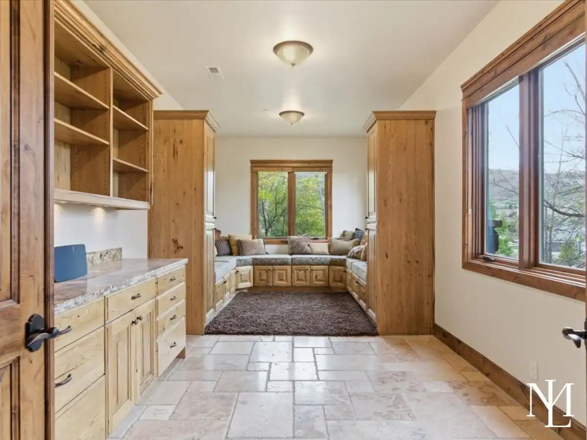 Built-in office and reading nook with custom cabinetry, stone tile floors, and cushioned window seating.