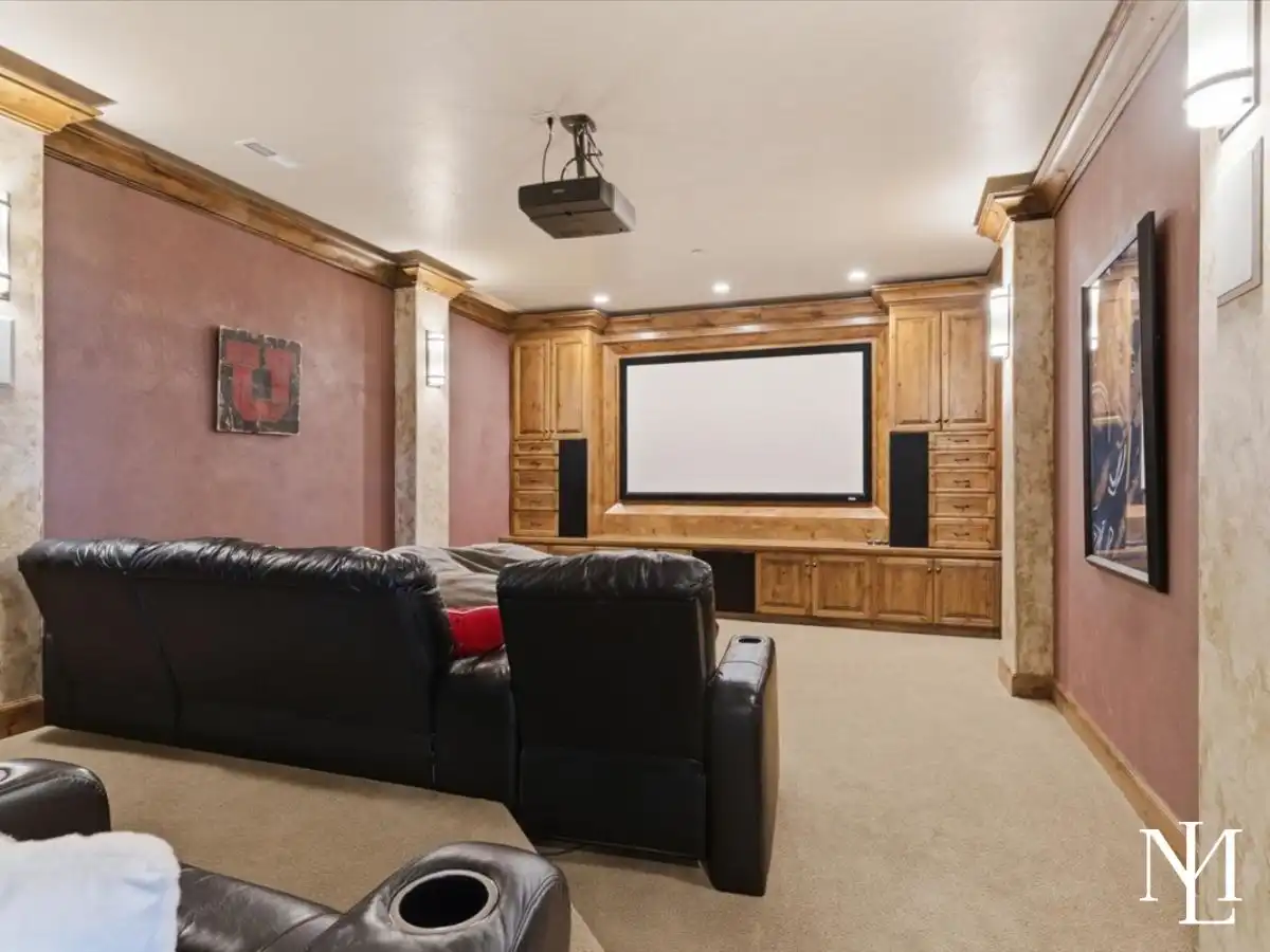 Private theater room with projector, large screen, built-in cabinetry, and plush seating for movie nights at home.