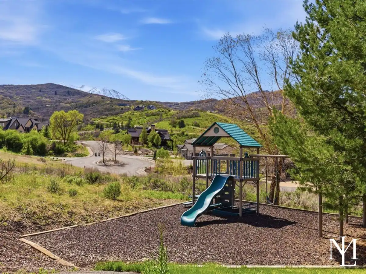 Backyard play area with slide and play structure overlooking a quiet mountain neighborhood and scenic foothill views.