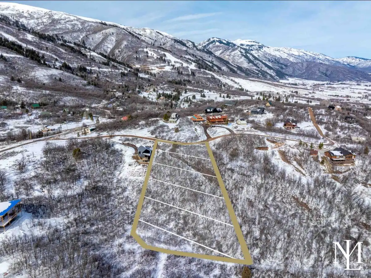 Aerial view of wooded Eden homesite outlined near Nordic Valley with snow-covered mountain slopes and Ogden Valley views