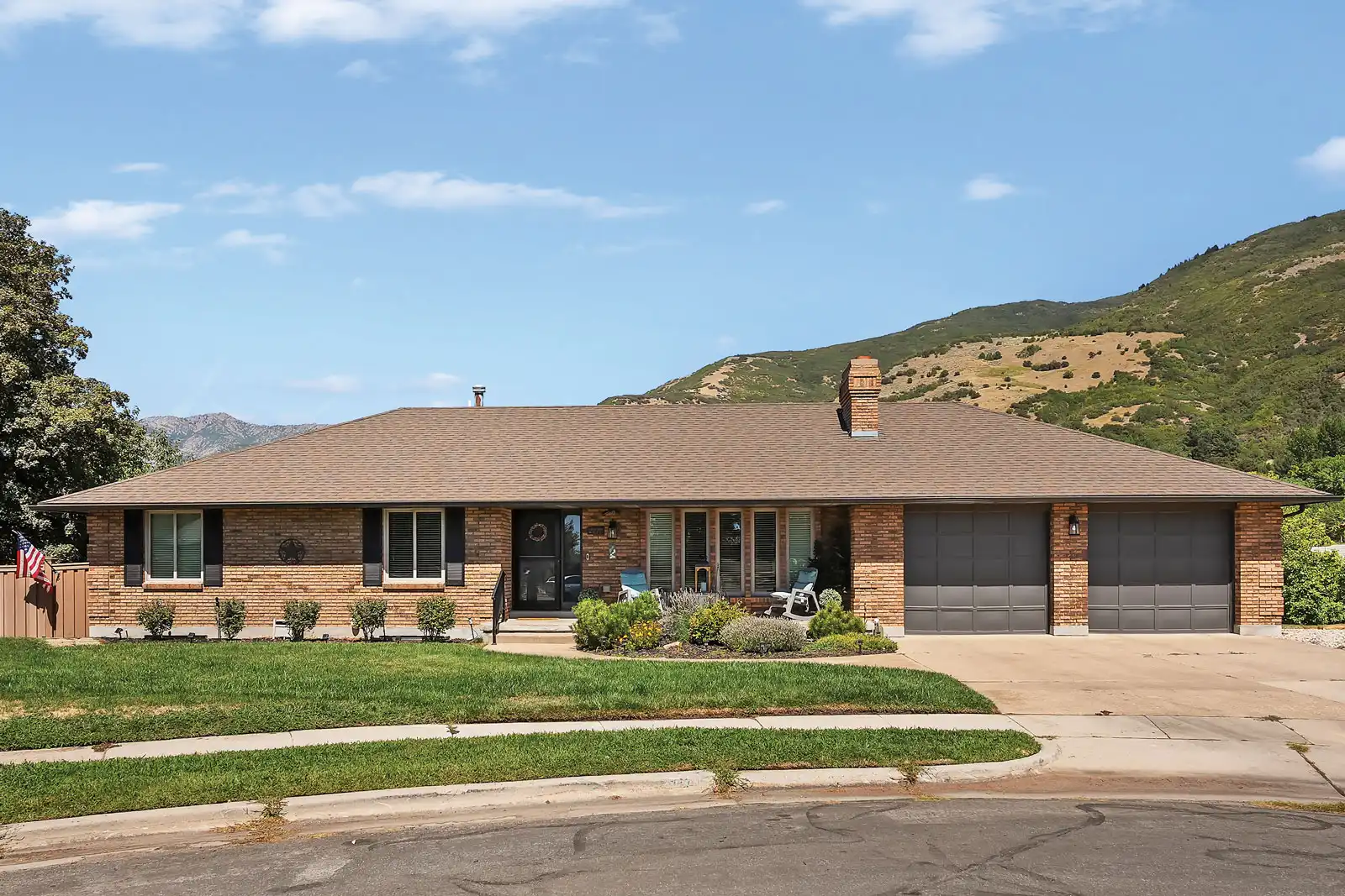 The front of 2777 E 2700 N during mid-day with harsh shadows, a two car garage, and entry constructed of brick.