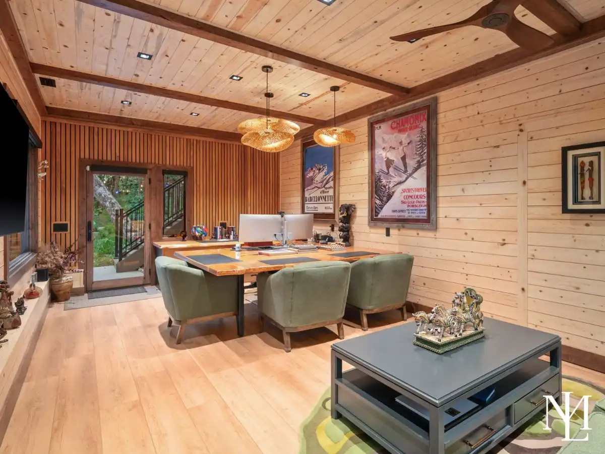 Wood-paneled office or studio space with modern workstations, warm cabin finishes, and direct outdoor access.