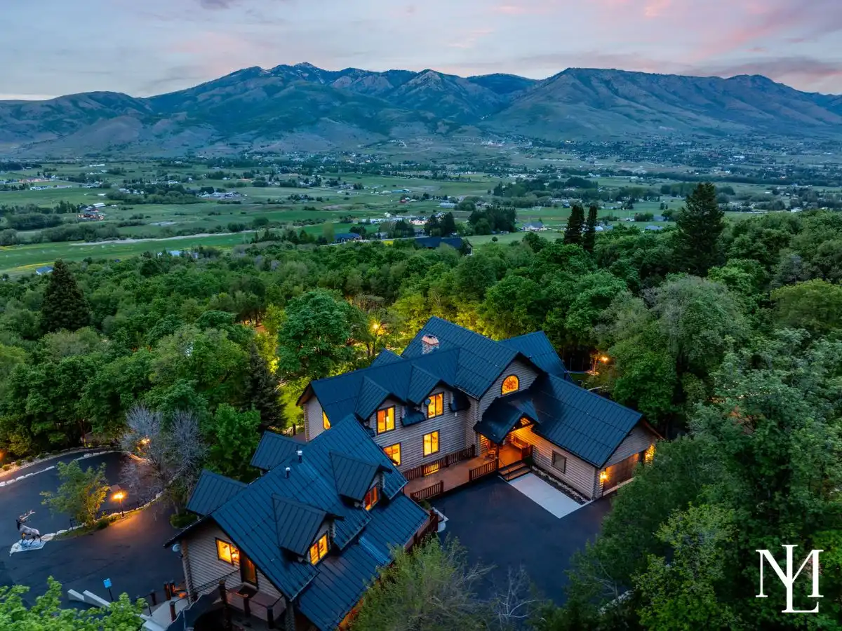 Aerial twilight view of a private Liberty, Utah mountain retreat surrounded by trees with panoramic Ogden Valley and mountain views.