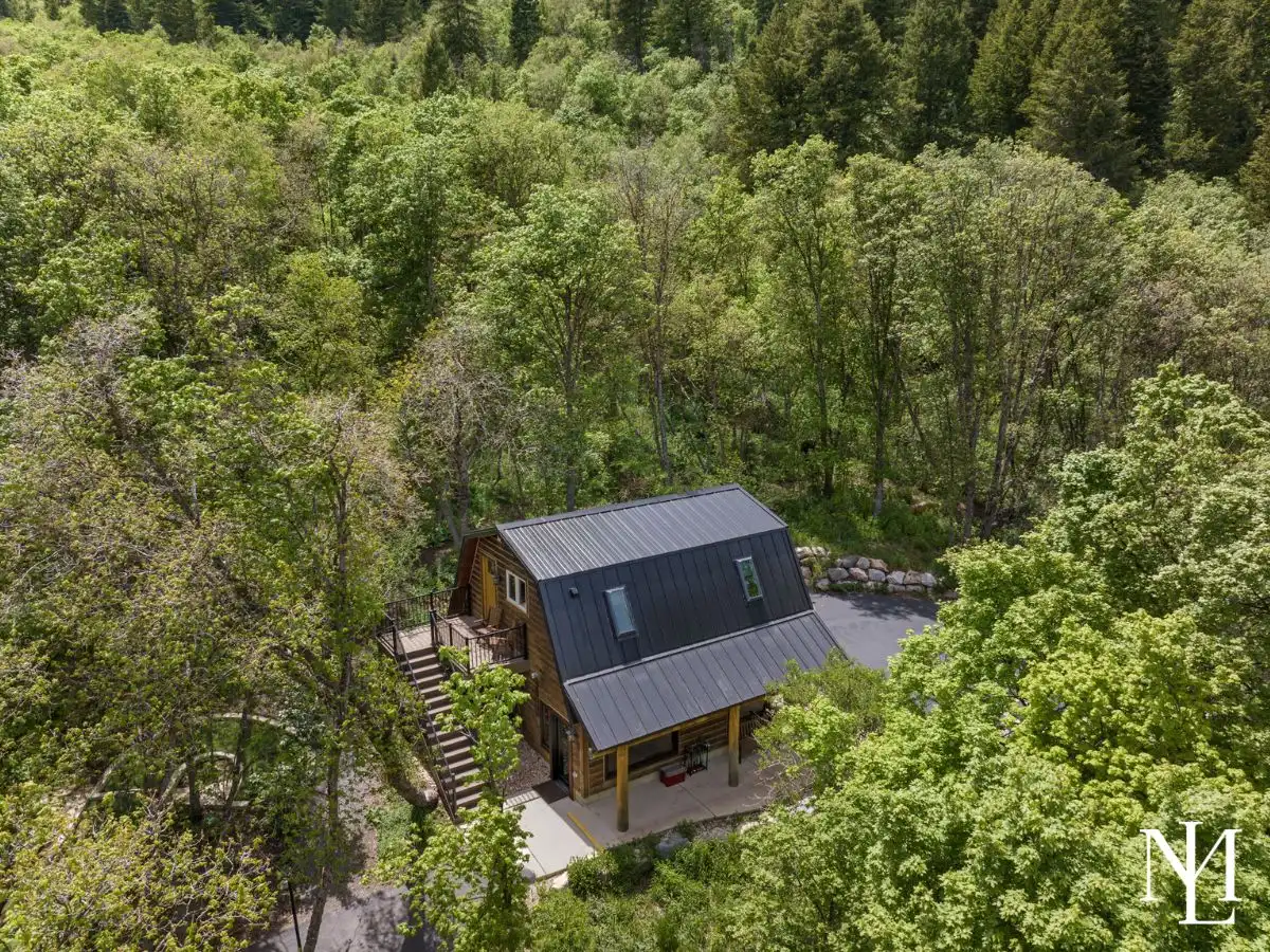 Aerial view of a private guest cabin tucked into the trees on a wooded Liberty, Utah mountain property.