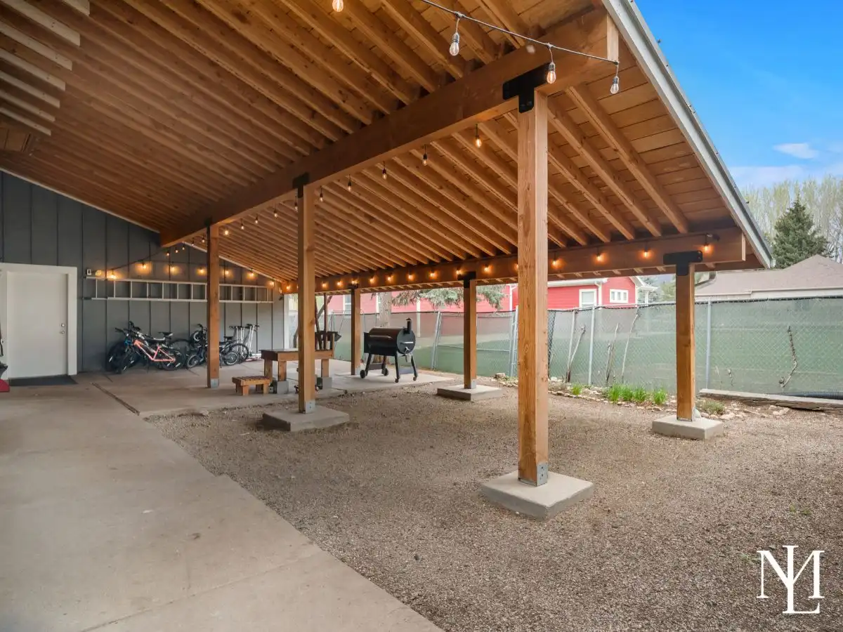 Covered outdoor pavilion with exposed wood beams, string lighting, and space for dining or gathering year-round.
