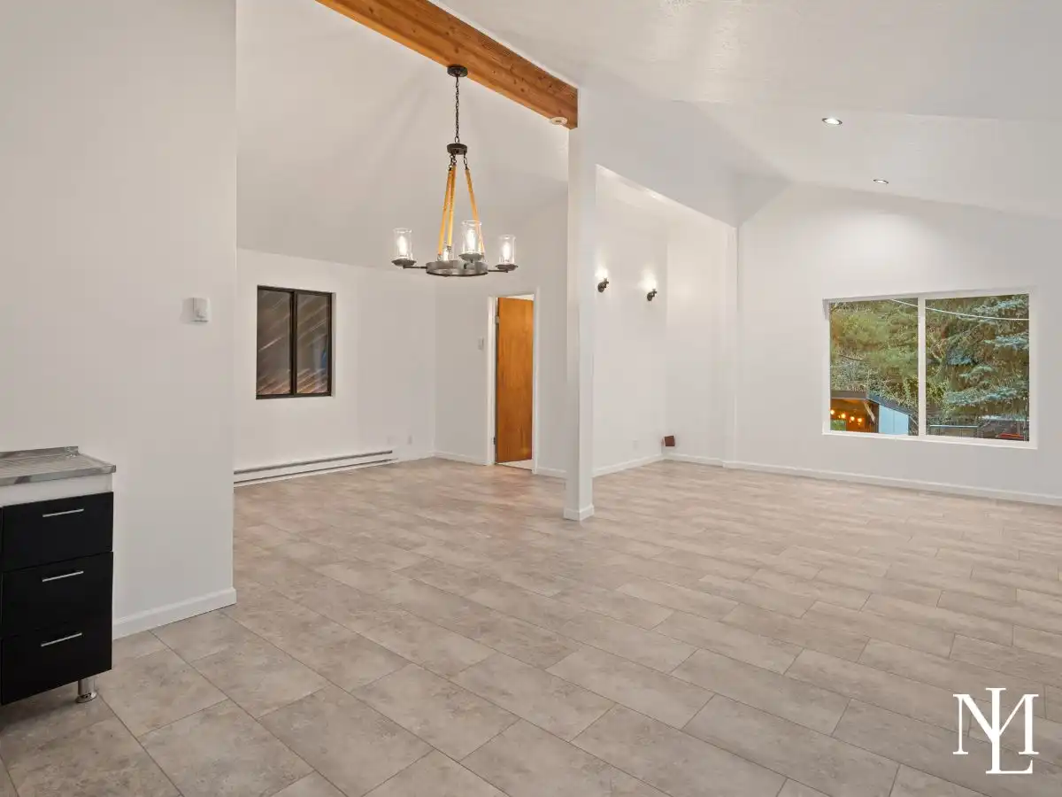 Spacious lower-level flex room with tile flooring, high ceilings, and open layout for recreation or gathering.