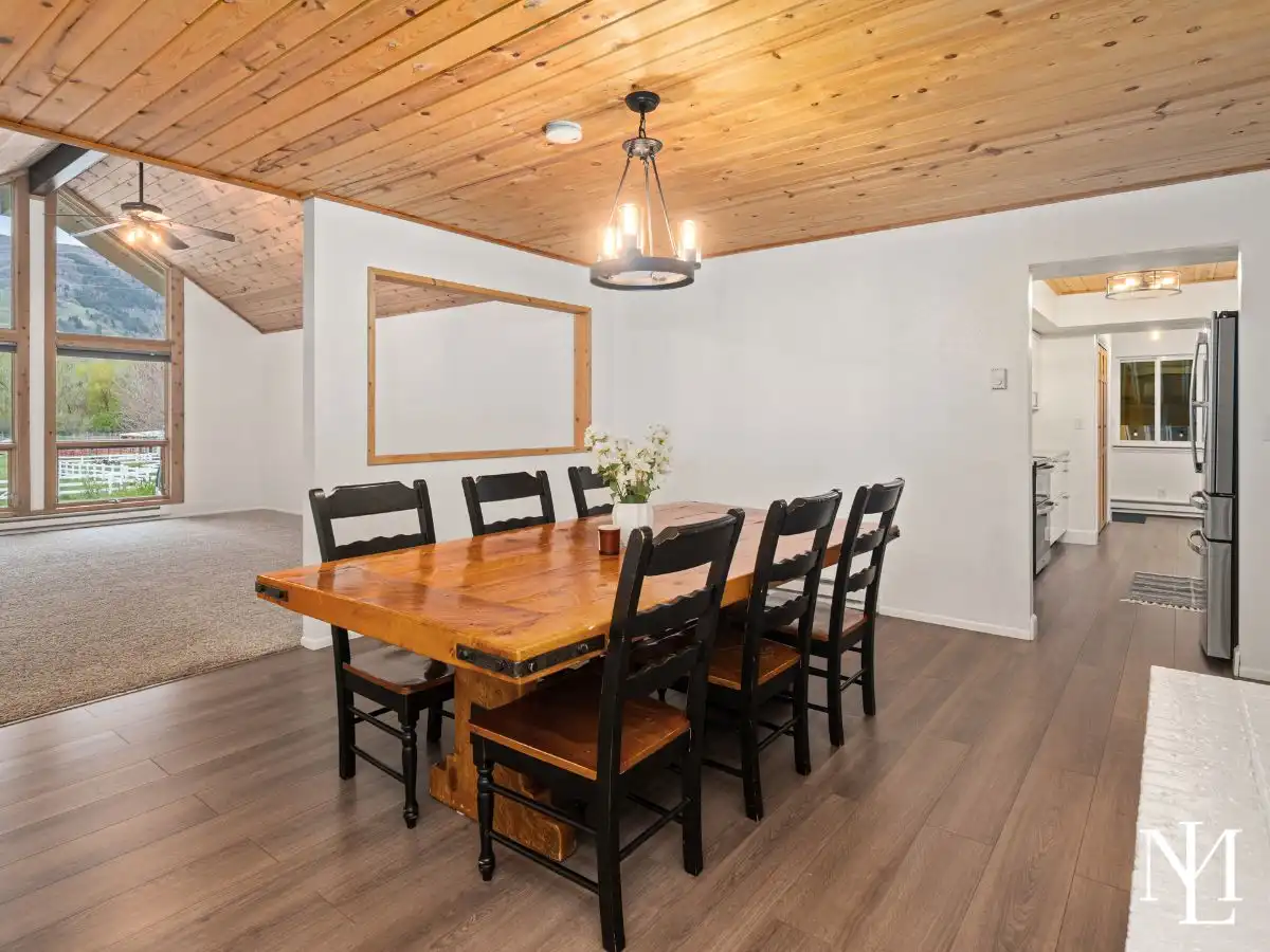 Dining area with warm wood ceiling and open flow into living space in updated Eden, Utah mountain home.