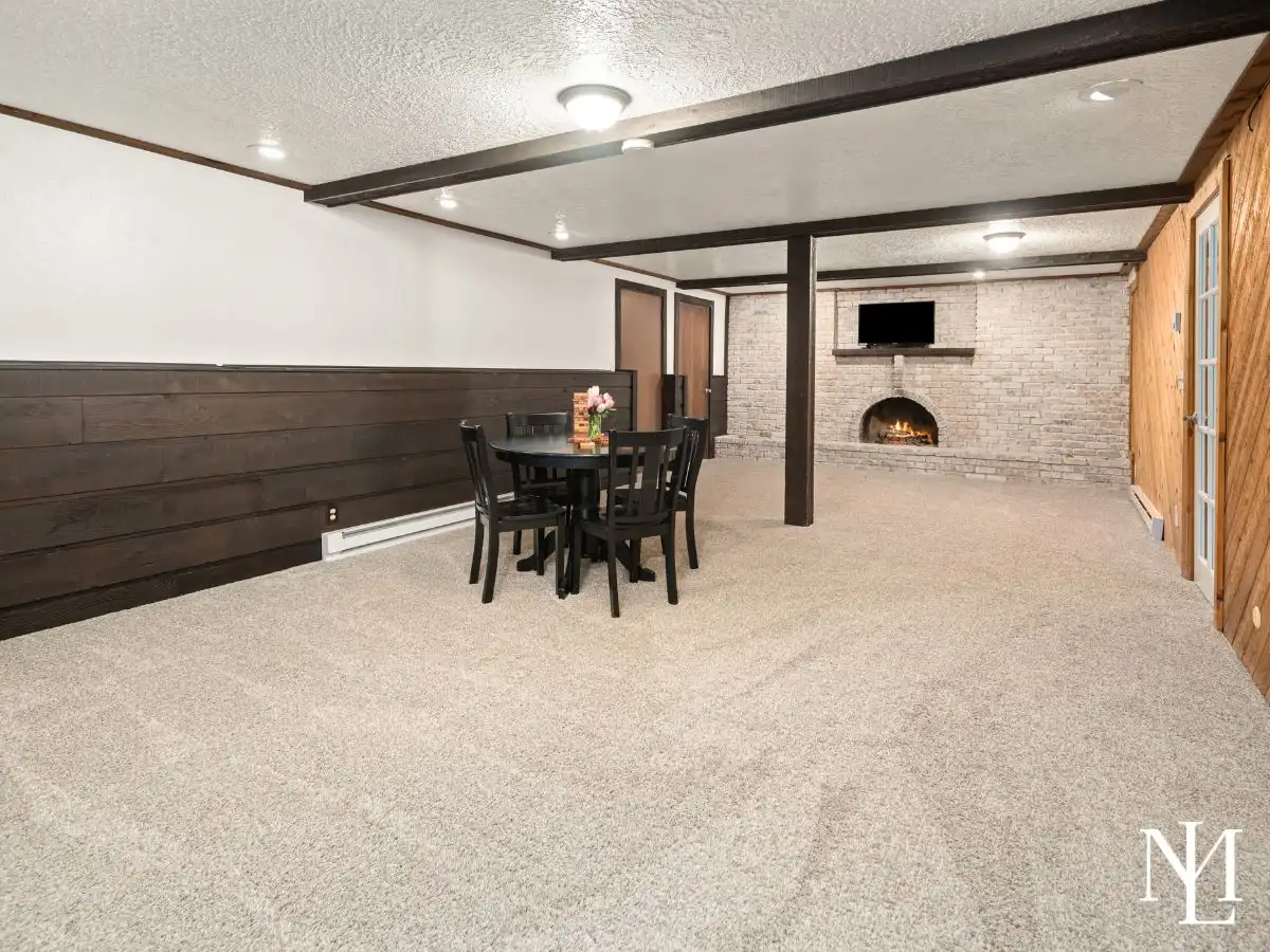 Large family room with fireplace, wood accent walls, and generous entertaining space in finished basement.