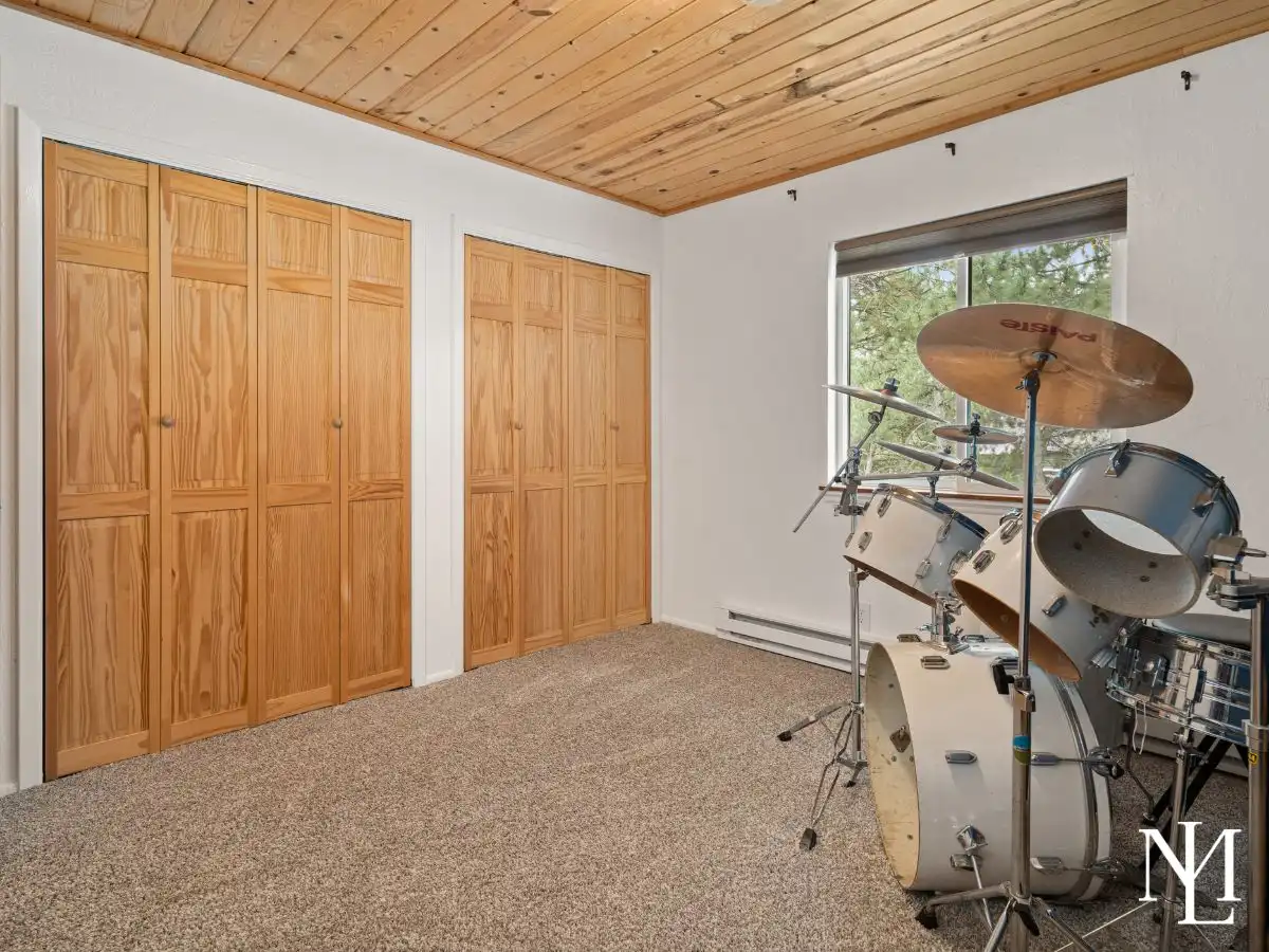 Flexible bedroom or studio space with wood ceiling, natural light, and built-in pine closet doors in Eden home.