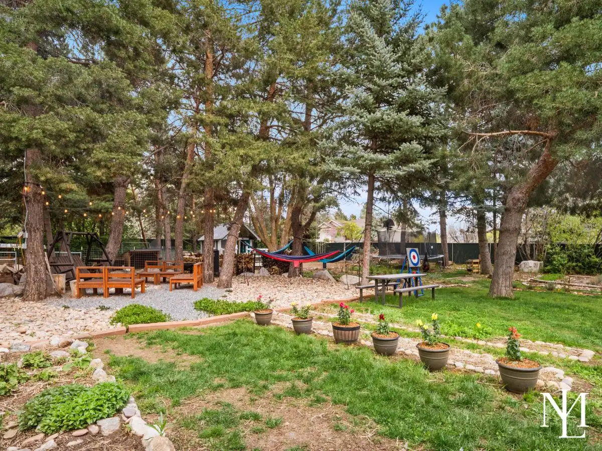 Private backyard retreat with mature pine trees, seating area, hammock, and garden setting in Eden, Utah.