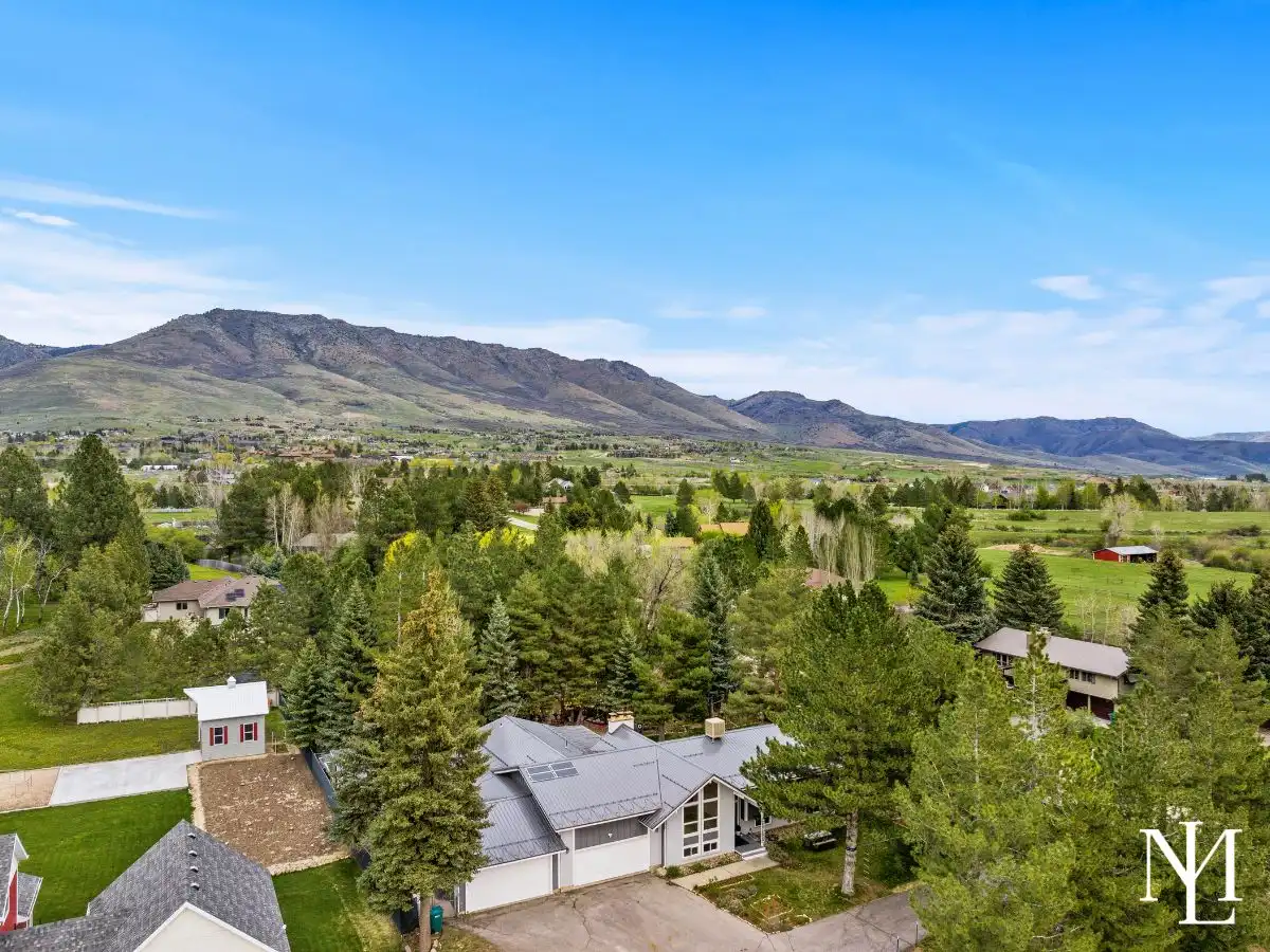 Aerial view of private Eden, Utah property with mature trees, open valley landscape, and sweeping mountain views in Ogden Valley.