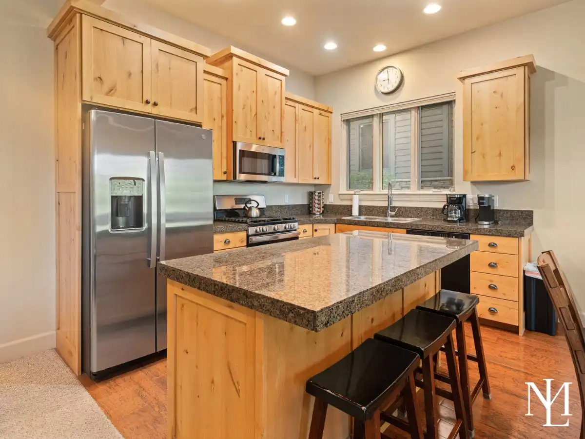 Turnkey Eden Utah kitchen with knotty wood cabinetry, granite island, stainless steel appliances, and bar seating