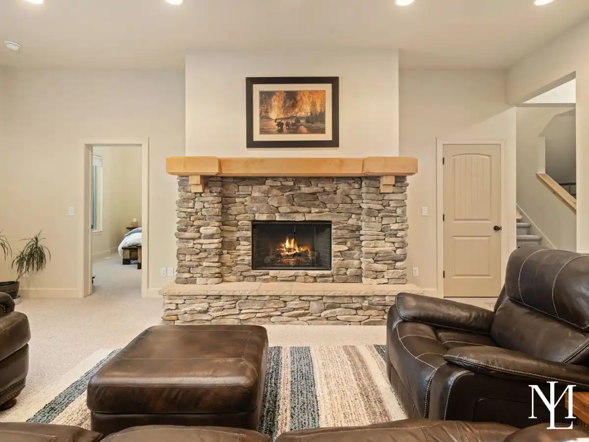 Living room in Trapper’s Ridge home with stone fireplace, leather seating, and warm mountain lodge finishes