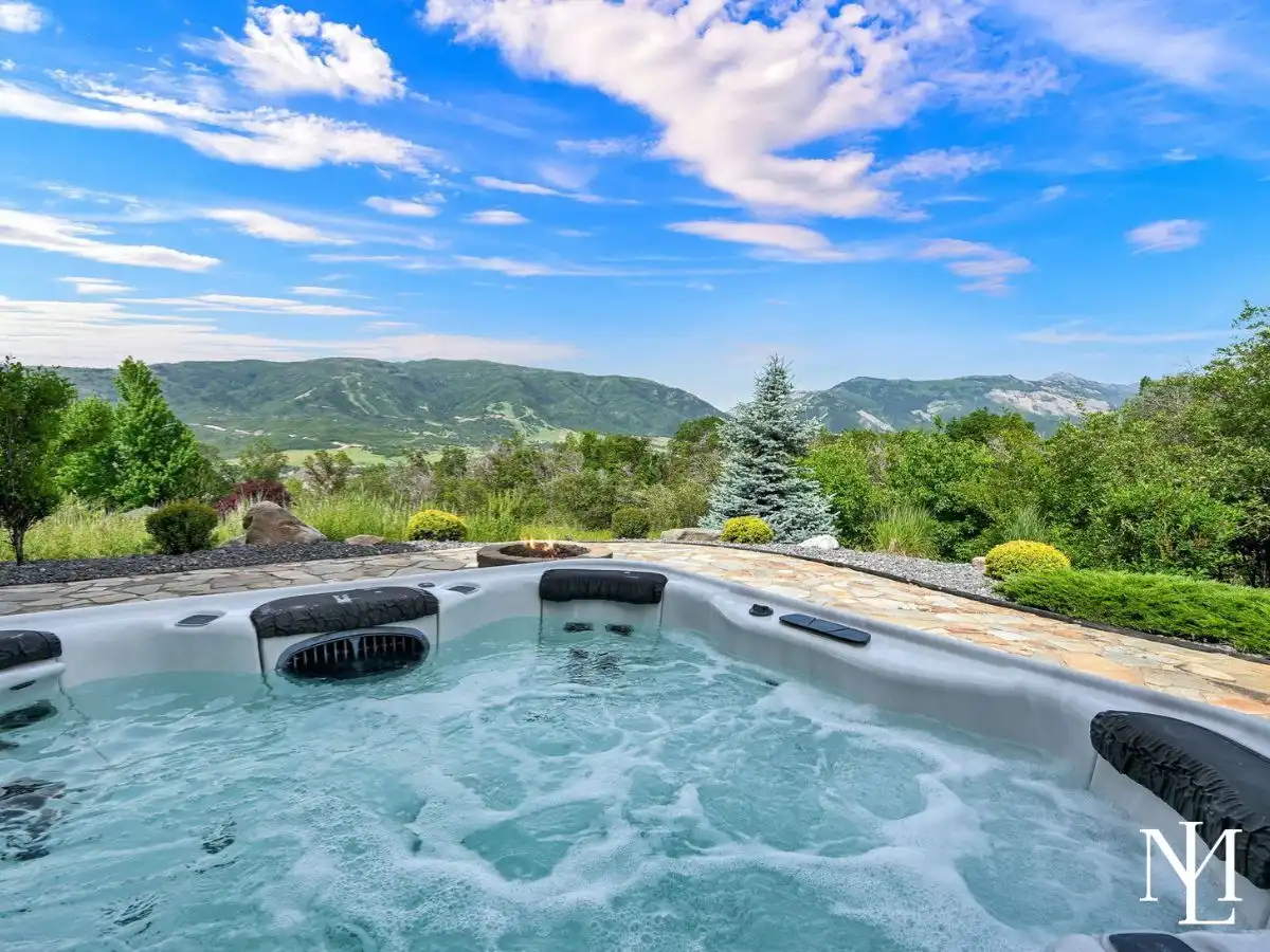 Private hot tub patio in Eden Utah with mountain views, fire pit, and landscaped outdoor living space