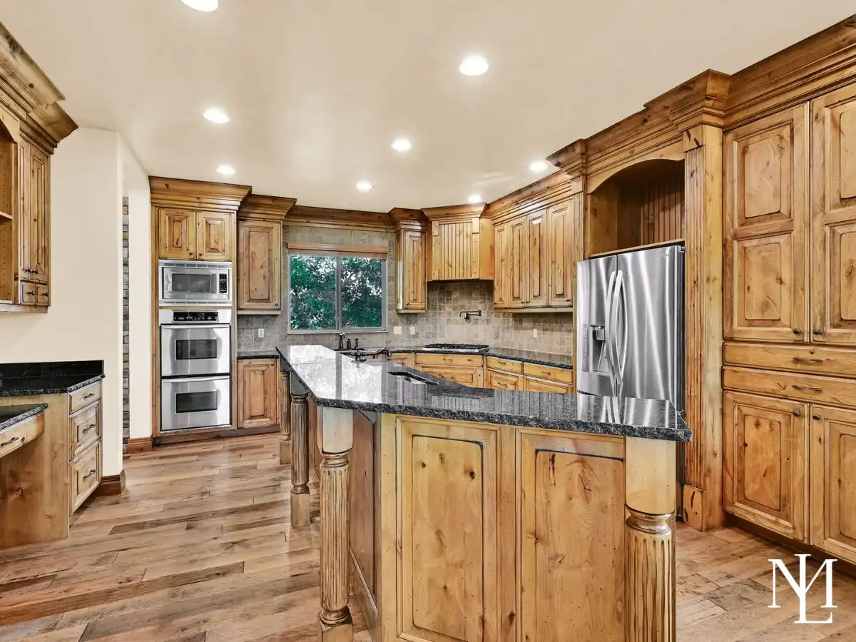 High-end kitchen in Eden Utah home with custom wood cabinetry, granite countertops, double ovens, and hardwood floors
