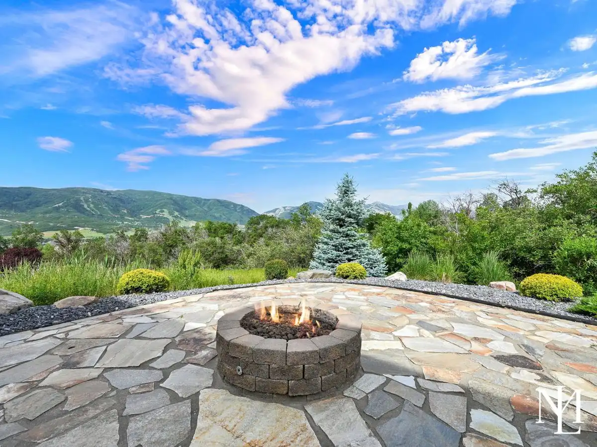 Stone patio in Eden Utah with fire pit, professional landscaping, and views toward Nordic Valley and Ogden Valley mountains