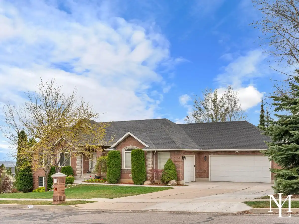 Front exterior of brick rambler home in Pleasant View, Utah with landscaped yard and attached 3-car garage.