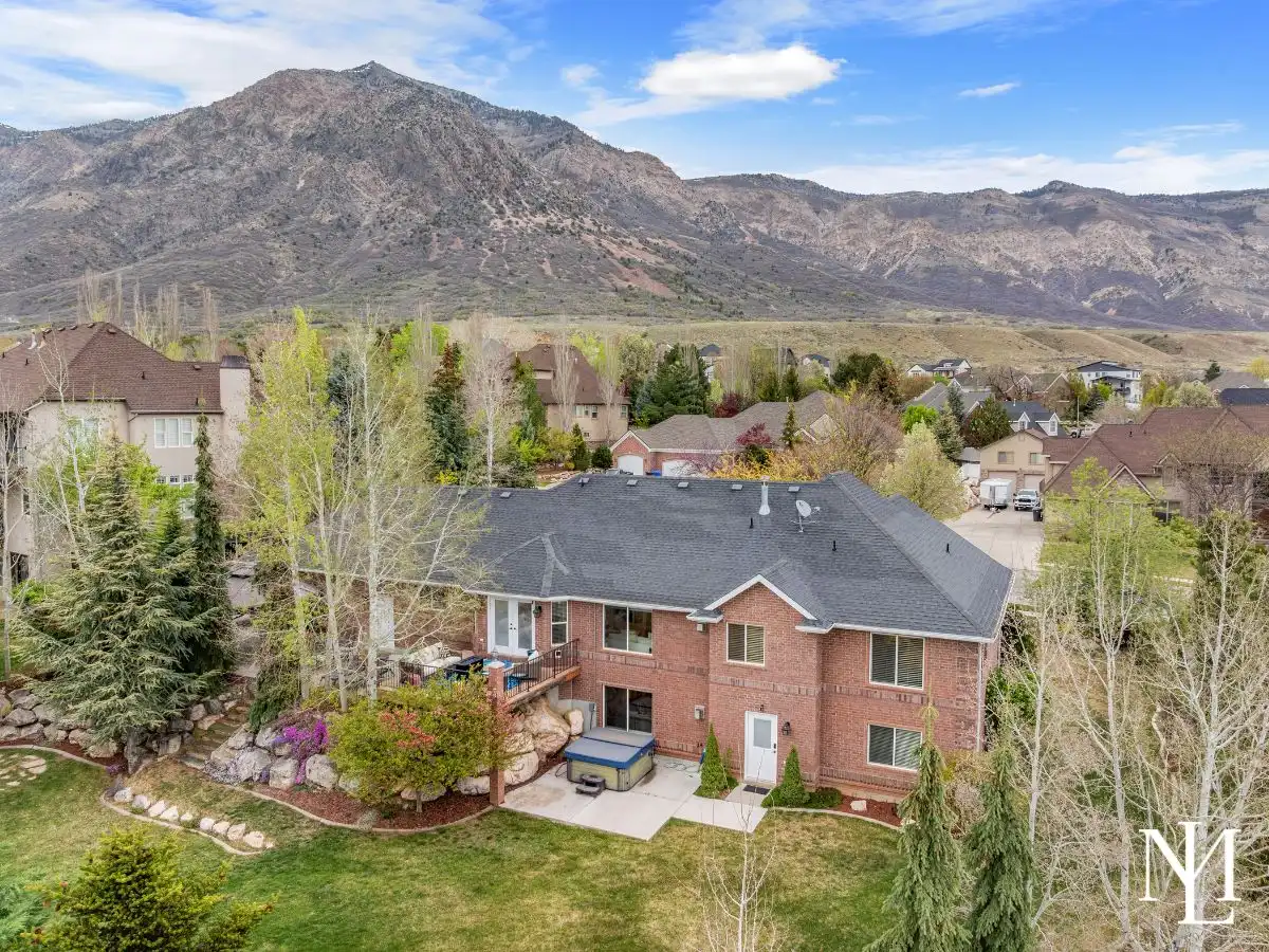 Rear exterior of Pleasant View rambler with walkout basement, patio, hot tub, and mature landscaping.
