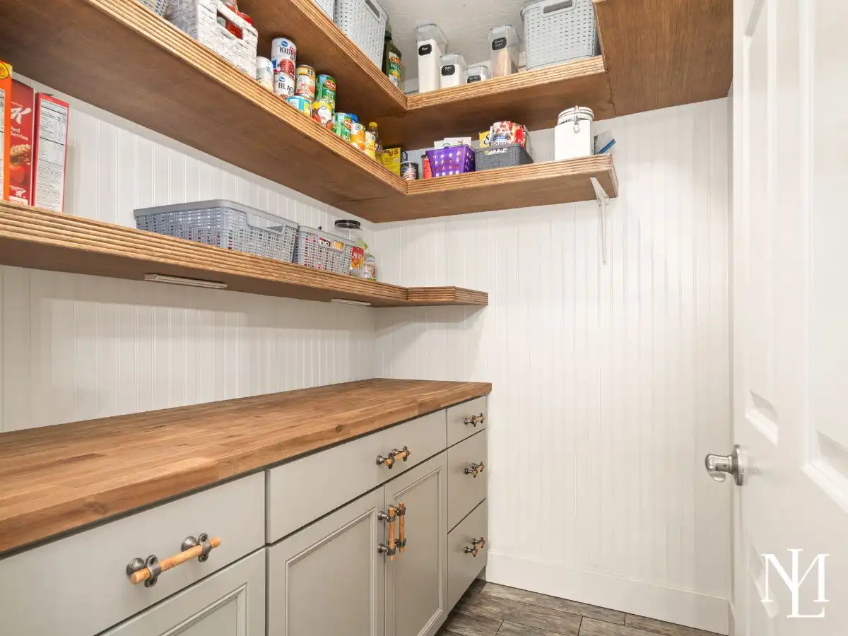 Walk-in pantry with custom shelving, wood countertop workspace, and built-in storage.