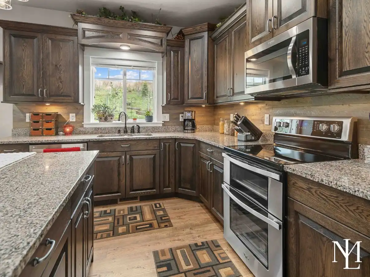 Kitchen with dark wood cabinetry, granite countertops, stainless steel appliances, and center island in Eden, Utah home.