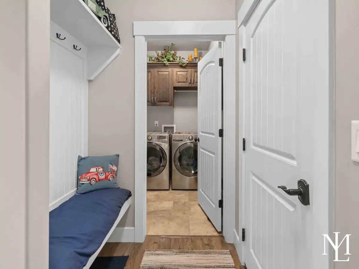 Mudroom entry with built-in bench and adjacent laundry room with upper cabinetry.