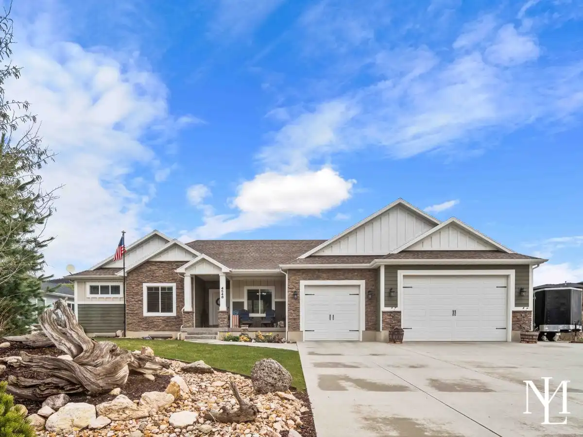 Front exterior of rambler home in The Preserve at Sheep Creek in Eden, Utah with 3-car garage and mountain setting.