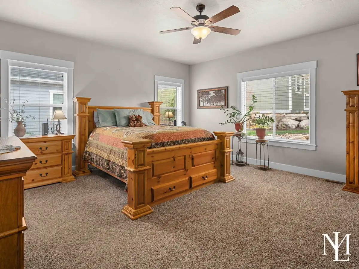 Alt text: Spacious primary bedroom with large windows, neutral finishes, and carpet flooring in Ogden Valley home.