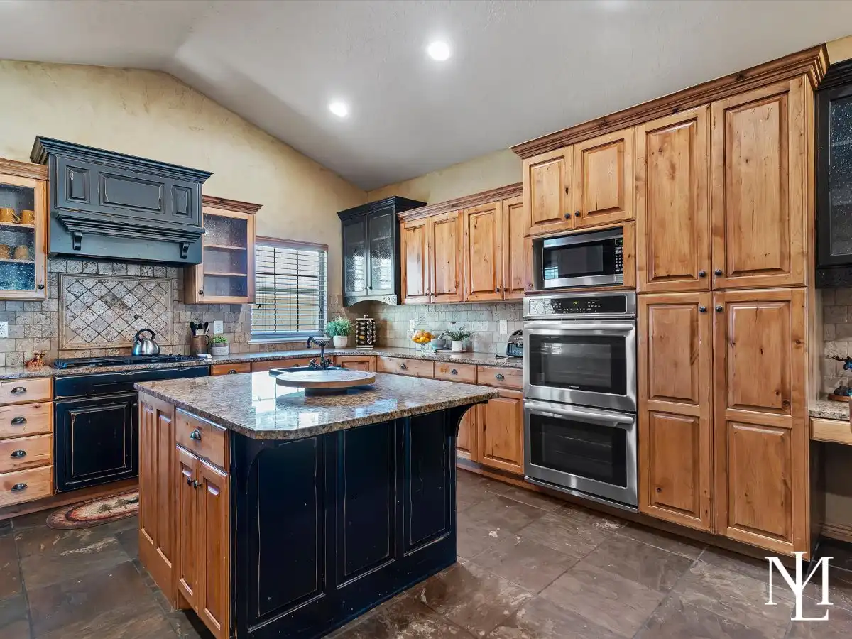 Rustic mountain kitchen with wood cabinetry, large island, granite countertops, and double wall ovens in Eden, Utah.