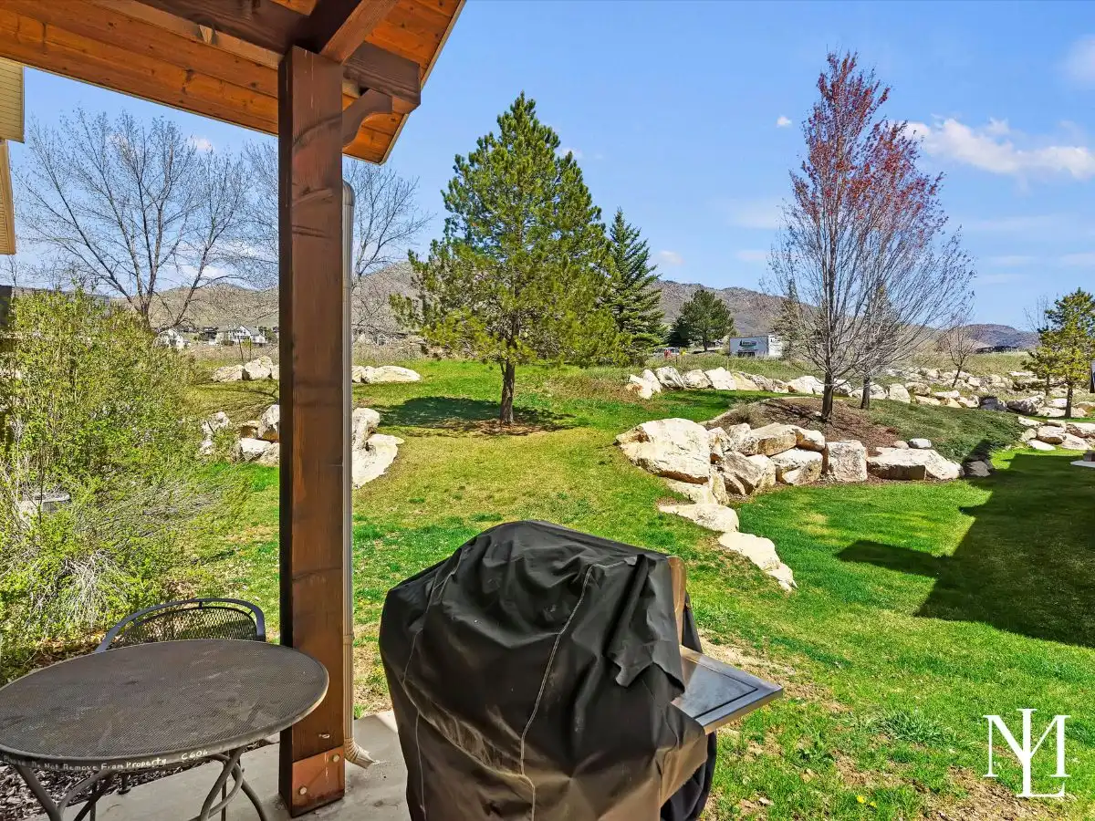 Covered patio with grill and open greenbelt-style views in mountain townhome setting in Eden, Utah.