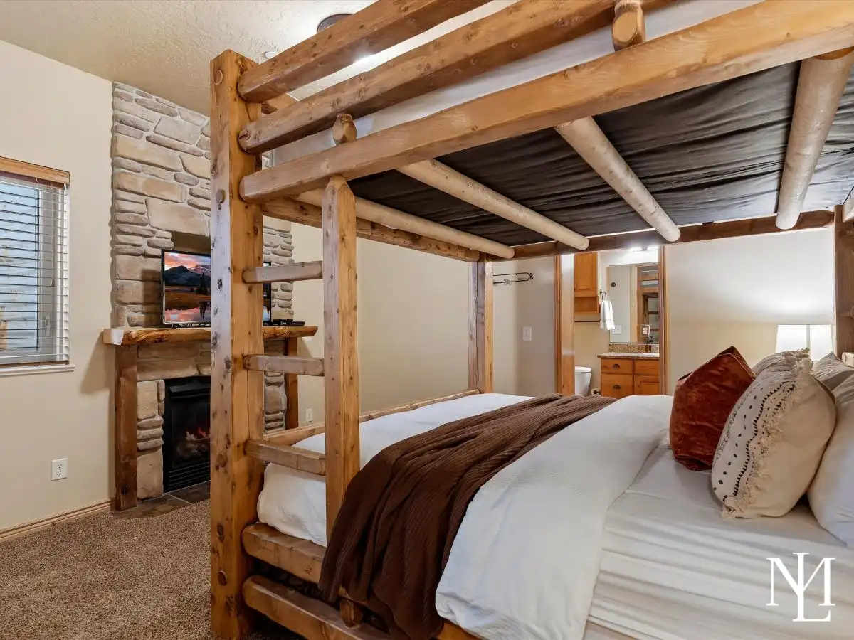 Bunk room with handcrafted log-style bed, fireplace, and ensuite bath in spacious Eden, Utah vacation townhome.