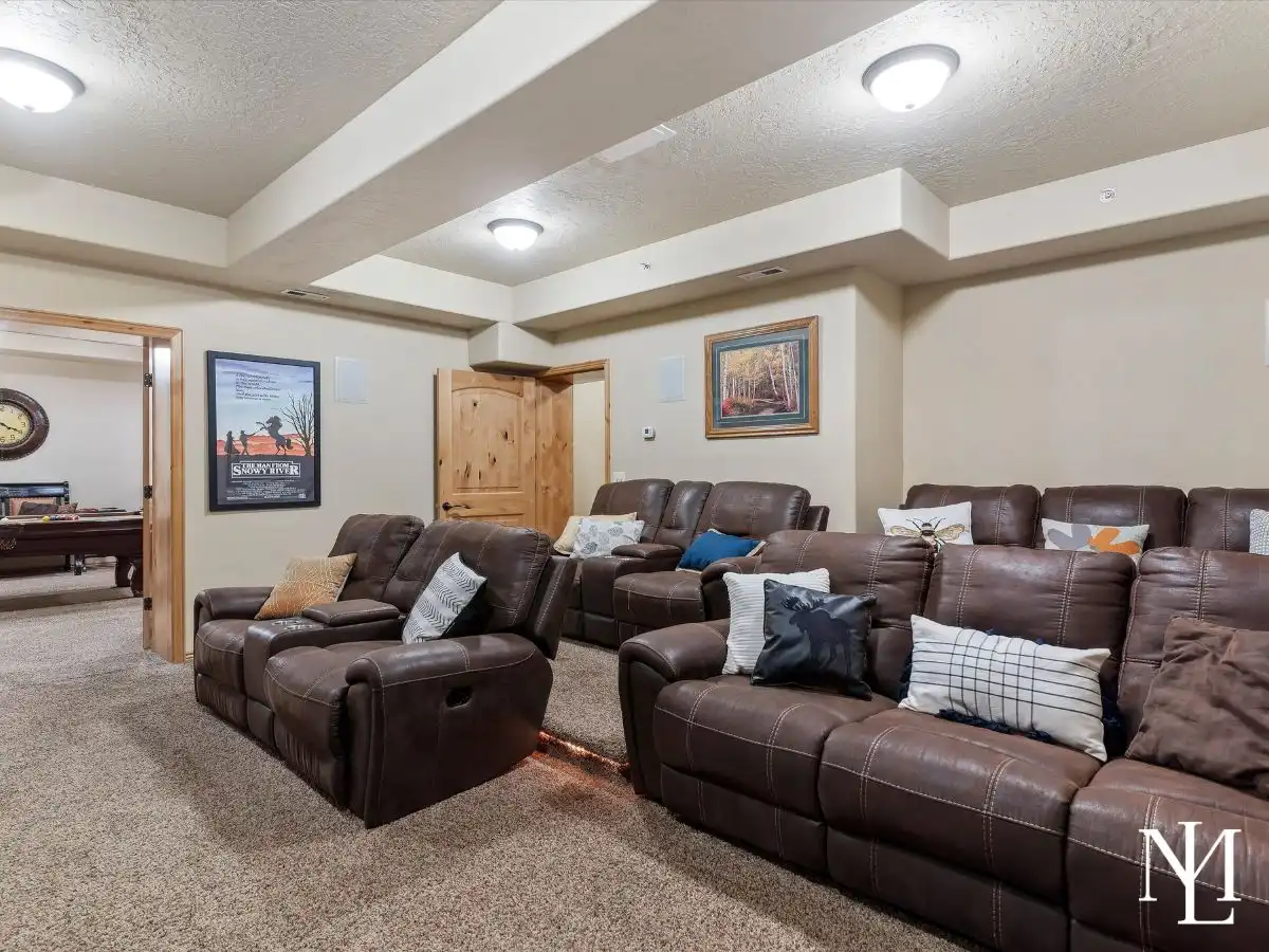 Theater room with plush recliner seating and media setup in finished lower level of Eden, Utah townhome.
