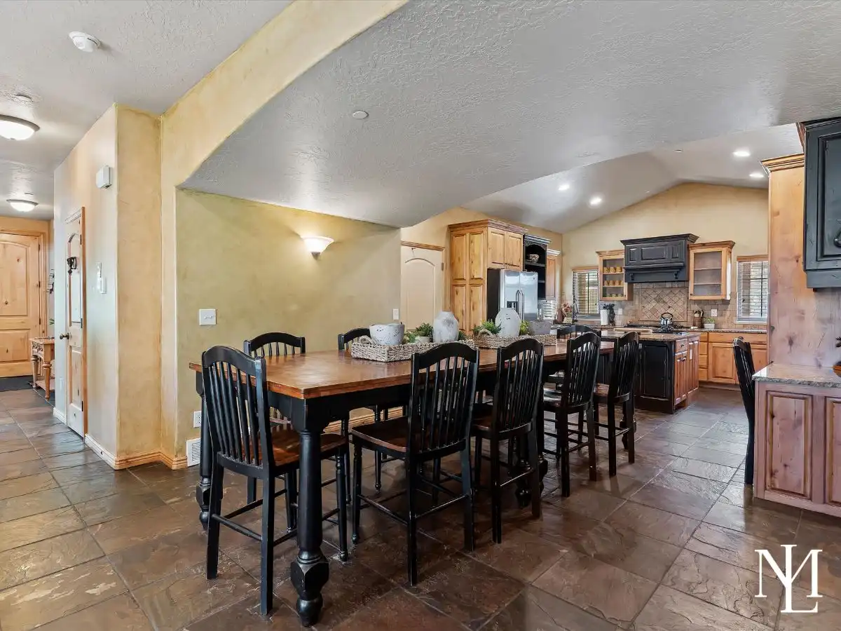 Open dining area with large gathering table and seamless flow into the kitchen in Wolf Creek townhome in Eden, Utah.