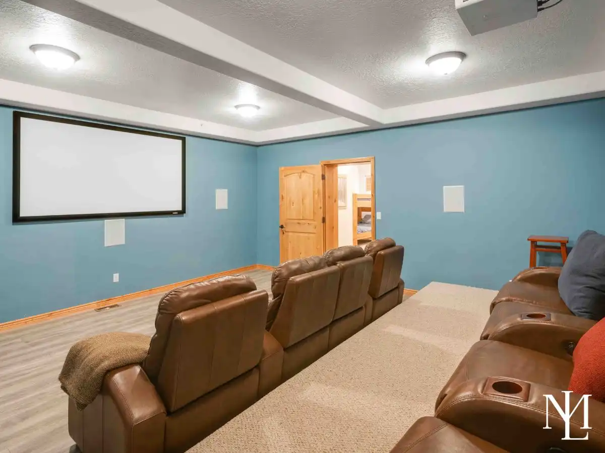Home theater room with projector screen and leather recliner seating in The Cascades townhouse in Eden, Utah.