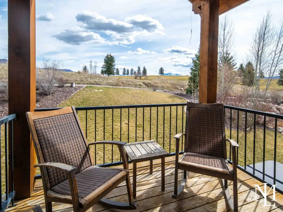 Covered balcony with two chairs overlooking landscaped green space near Wolf Creek Golf Course in Eden, Utah.