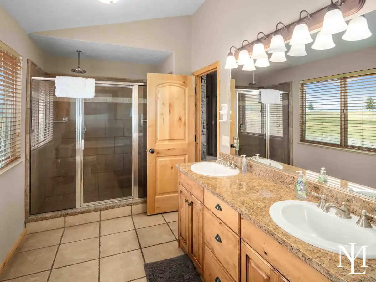 Bathroom with double-sink vanity, granite countertop, tile flooring, and glass shower in Eden, Utah townhome.
