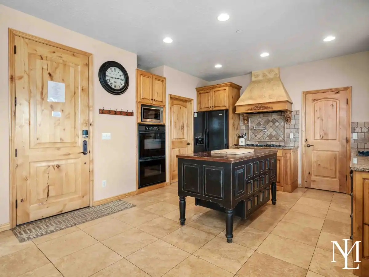 Kitchen with wood cabinets, tile backsplash, double wall ovens, and central island in The Cascades, Eden, Utah.