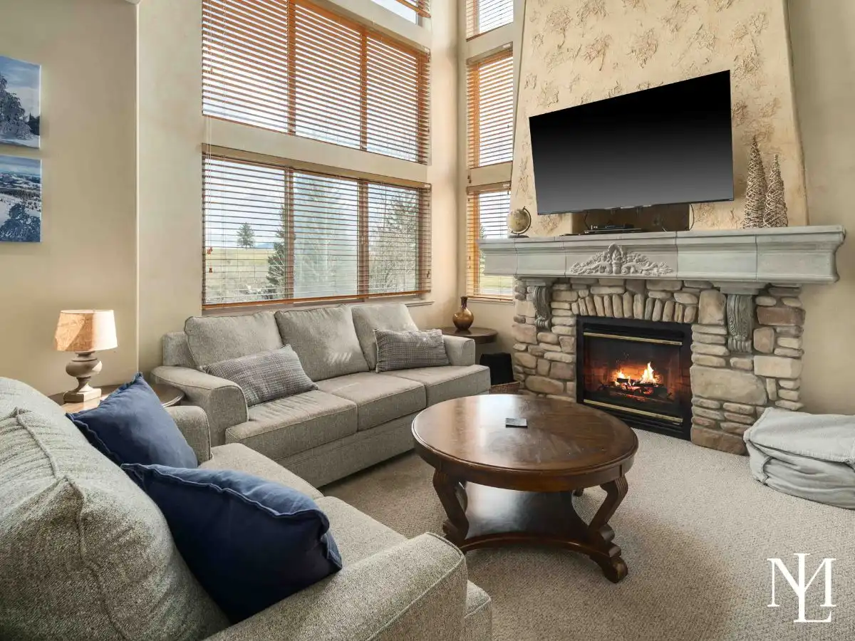 Living room with stone fireplace, vaulted windows, and comfortable seating in Eden, Utah golf community townhome.