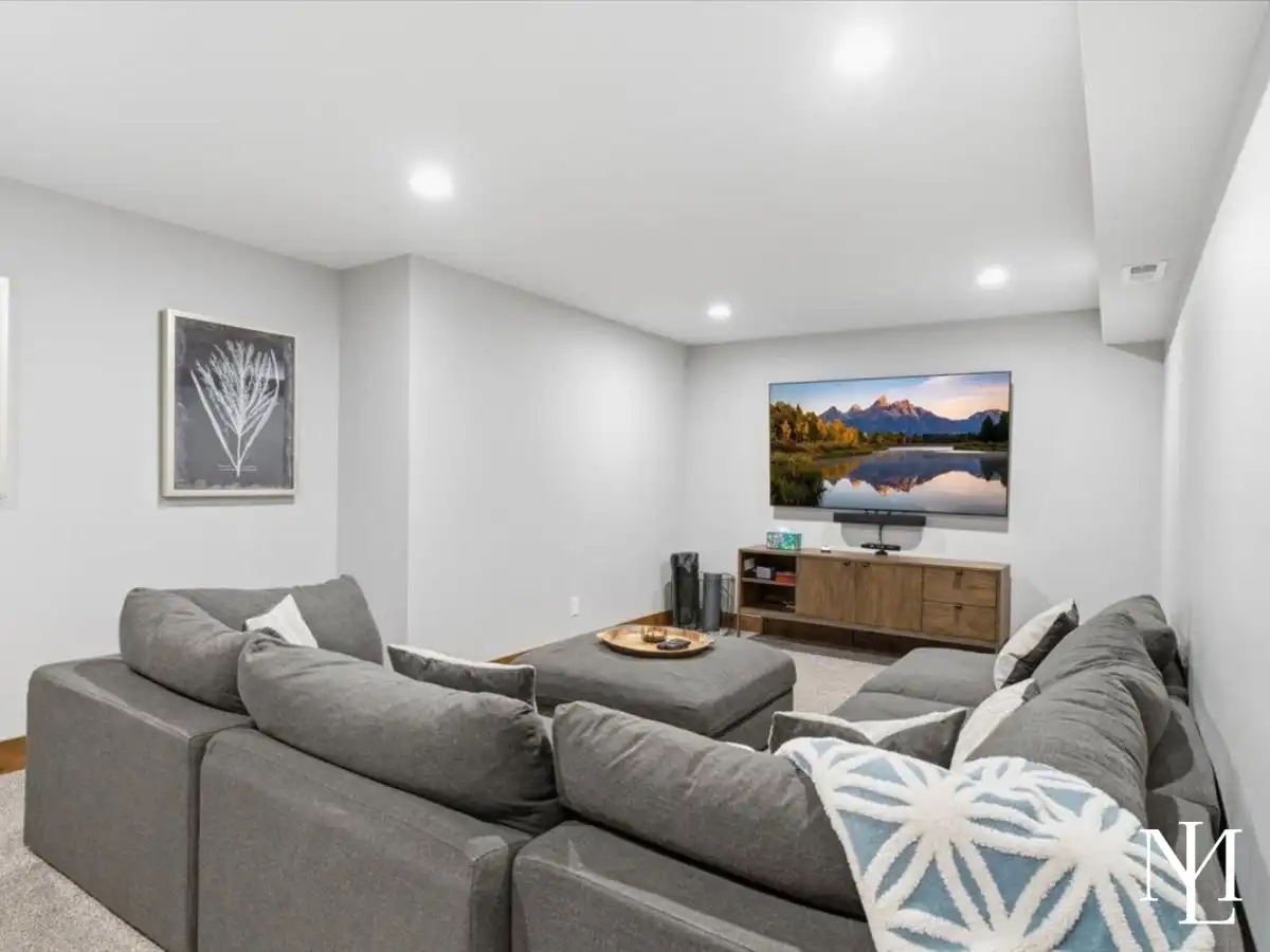 Lower-level family room with sectional sofa, media wall, and neutral finishes.