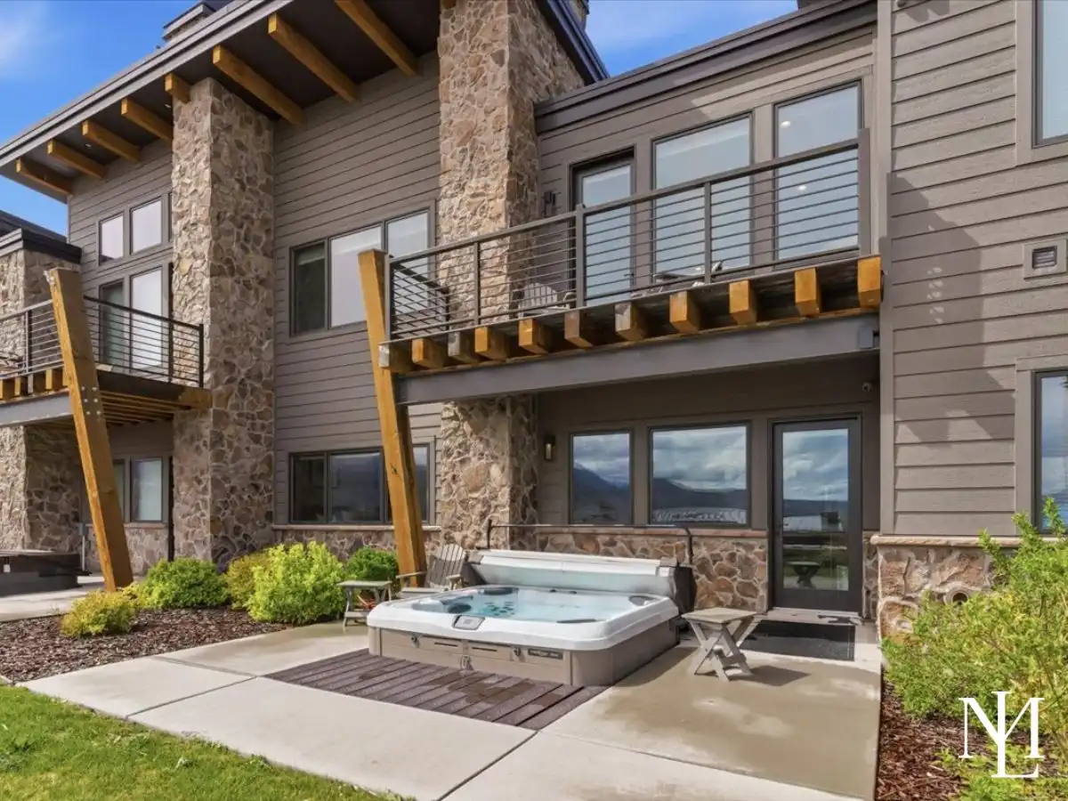 Private patio with hot tub, balcony, stone exterior, and mountain views in Eden, Utah.