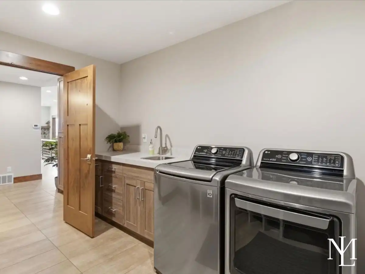 Laundry room with washer and dryer, sink, cabinetry, and tile flooring.