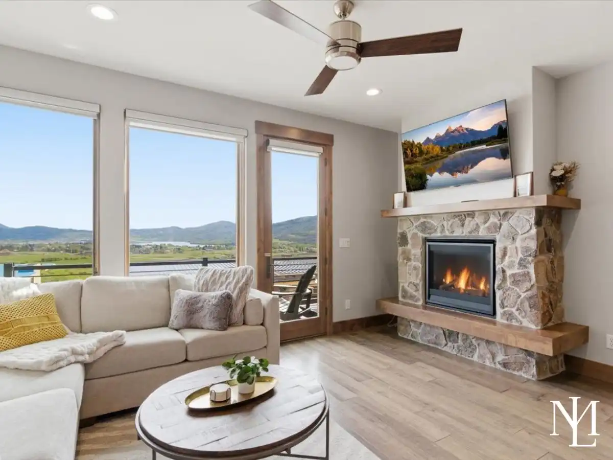 Living room with stone fireplace, large windows, and Pineview Reservoir views in Eden, Utah